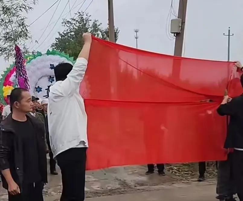 我老家安徽淮北，今天去河南走亲戚，看到一家办白事的人群停下来用一块红布遮挡住花圈