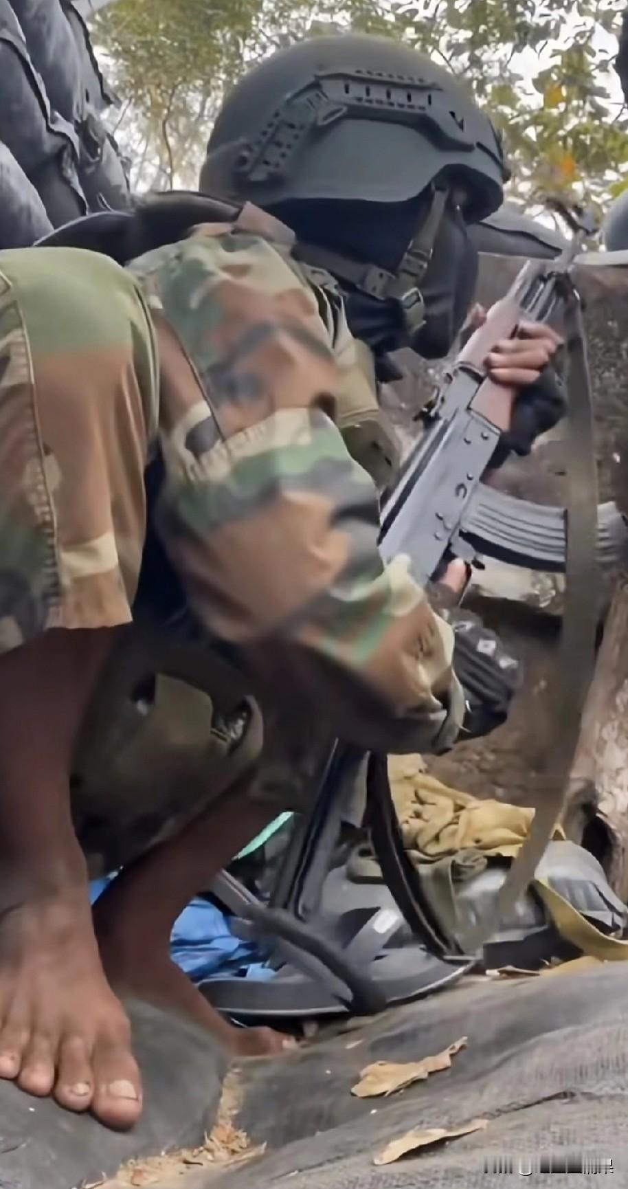 打仗穿成这样也真的是无语了，一名柬埔寨士兵在战壕里用AK突击步枪向外射击。看他