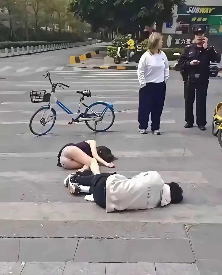 自行车相碰，两人同时倒地。其实只是两车轻微碰撞，谁都没有受伤，可是谁也不敢起来