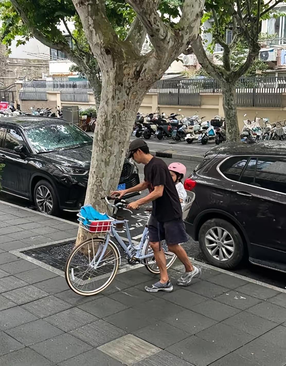 网友偶遇王阳骑单车接女儿放学遇到下雨天，带女儿到路房檐下避雨，父女二人同框画面好