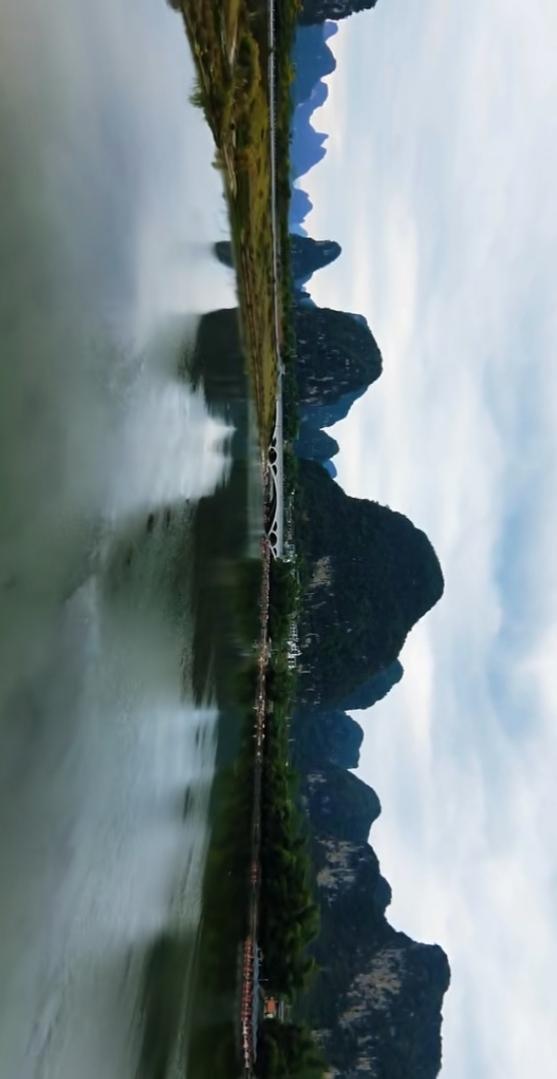 山峦倒影入江流，桥上行人似画中。