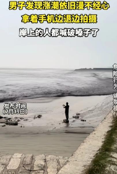 作死的节奏啊！已经涨潮，男子还驻足滩涂慢悠悠拍照。岸边围观的路人不停高声提醒，嗓