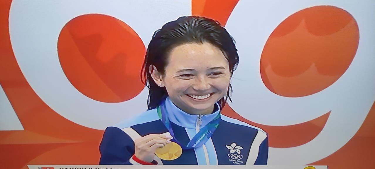 这个中国香港🇭🇰的游泳女运动员在亚运会上夺冠后兴高采烈、笑逐颜开，可在颁奖仪