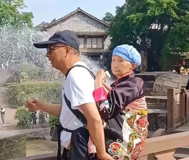 5月1日，于四川景区内，有一位大叔背着年届九旬的老母亲游览黄龙溪风景区。由于大叔