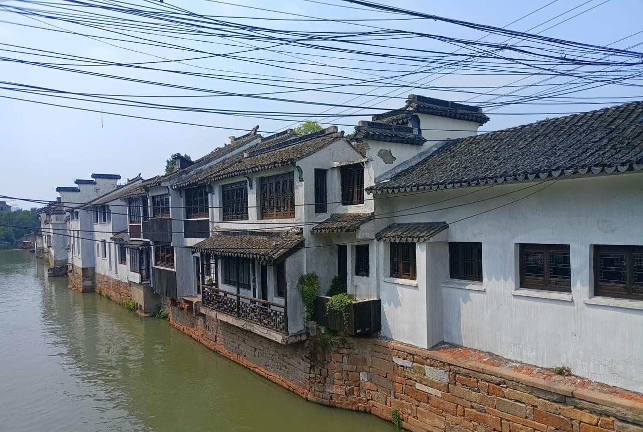 这照片是我去年四月在苏州拍的，站在桥上往下看，一条河，两排房。左边是马路，停着两