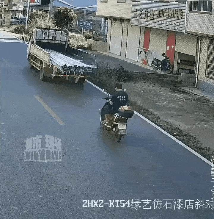 一个男子骑电动车，不戴安全帽，还一手拿着手机在看，前面停着一辆货车都没看到，直接