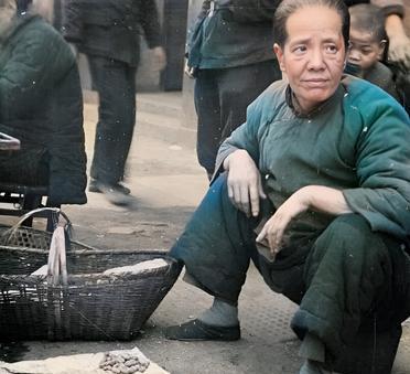 这是抗战时期日军镜头下一名小脚妇女在路边摆摊卖花生。这名小脚老太太从容貌上看神似