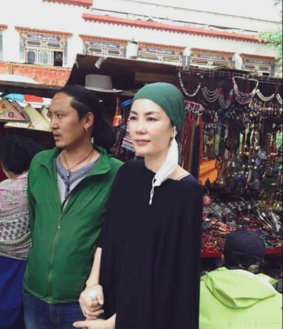 王菲西藏祈福头包绿色头巾，身穿黑色长袍。表情温和，慈眉善目。皮肤白皙胳膊纤细，天