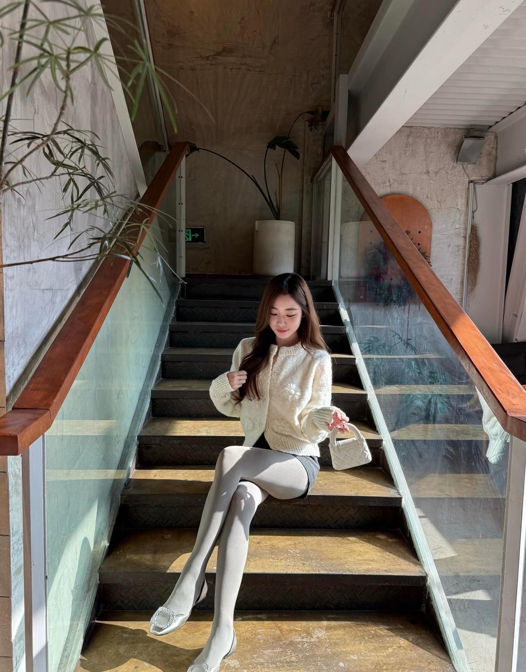 优雅坐楼梯，米色毛衣配长筒袜，尽显都市女性魅力！