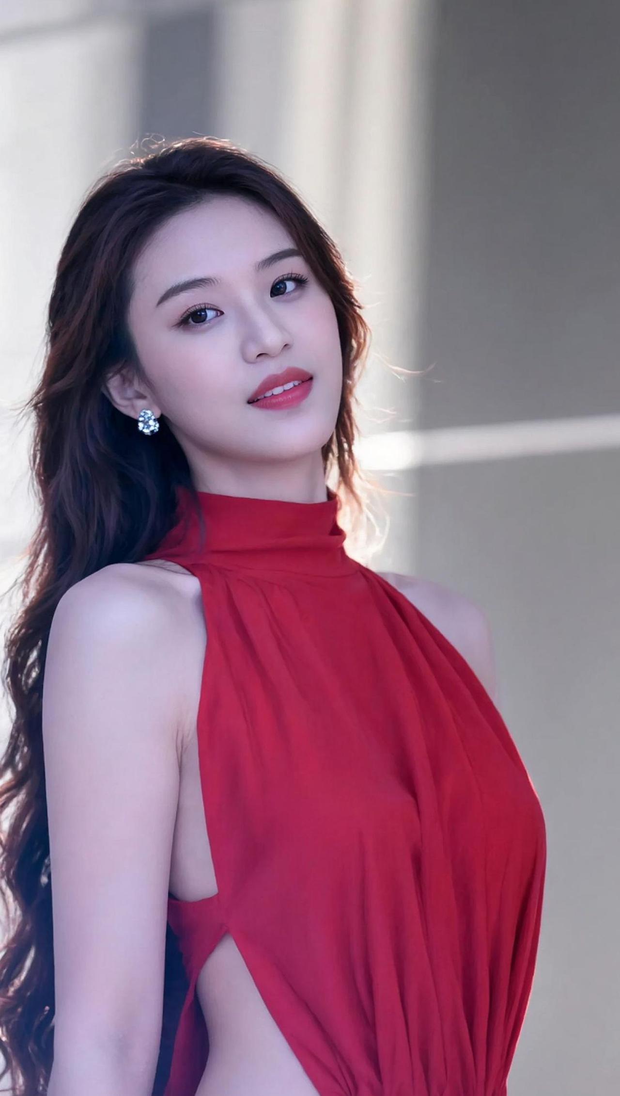 红色长裙如火焰般绽放，映衬出她的优雅与自信。背景模糊，仿佛时间静止，只为这一刻的