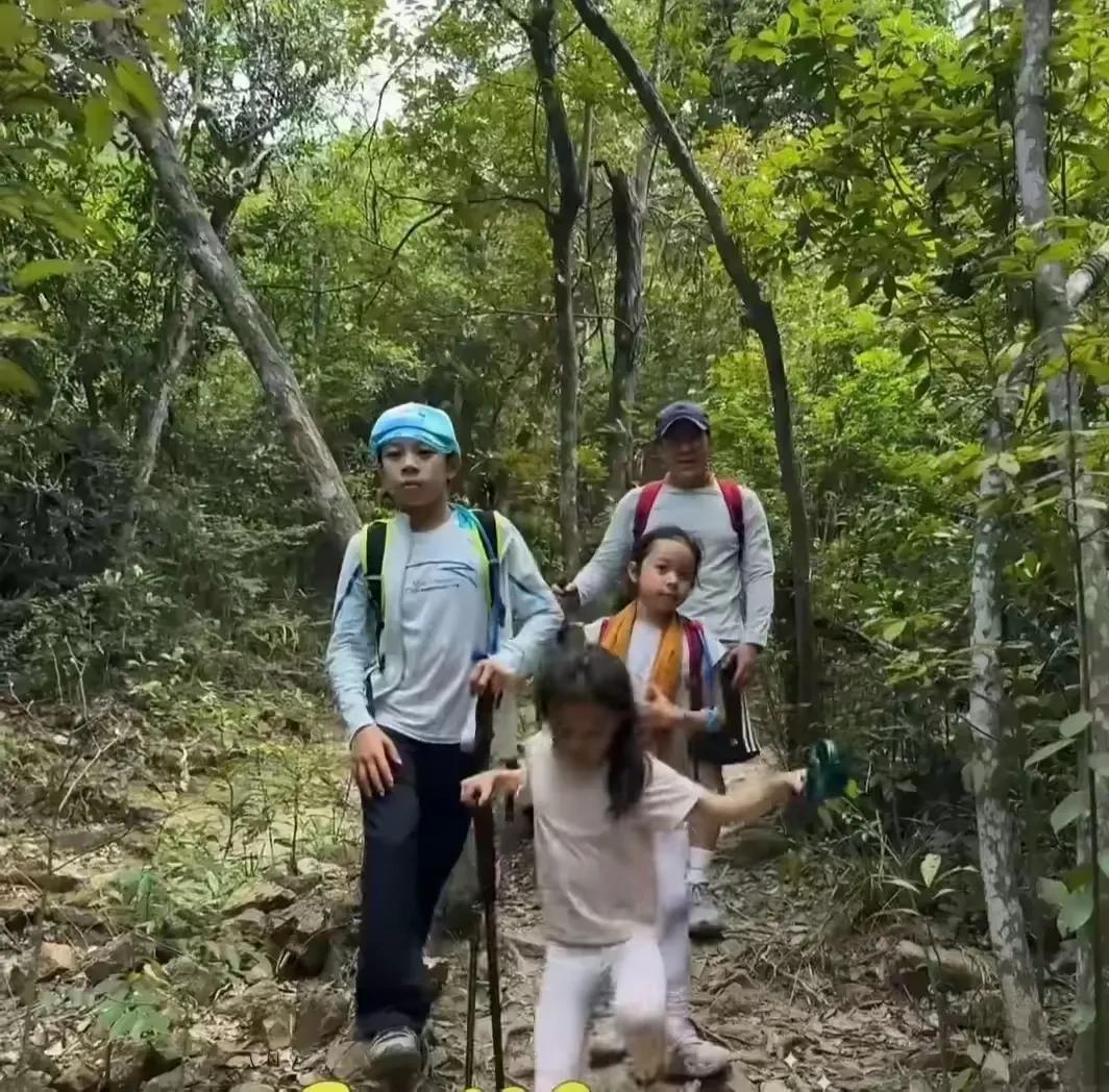五一假日，郭晶晶一家五口以山野为课堂：夫妻并肩开路，三子踉跄执杖攀阶，稚嫩手掌磨