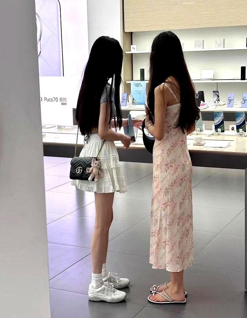 华为店里，冷气开得嗡嗡响。我一眼就看到了并排站着的那两个女孩。两个人都在看手机
