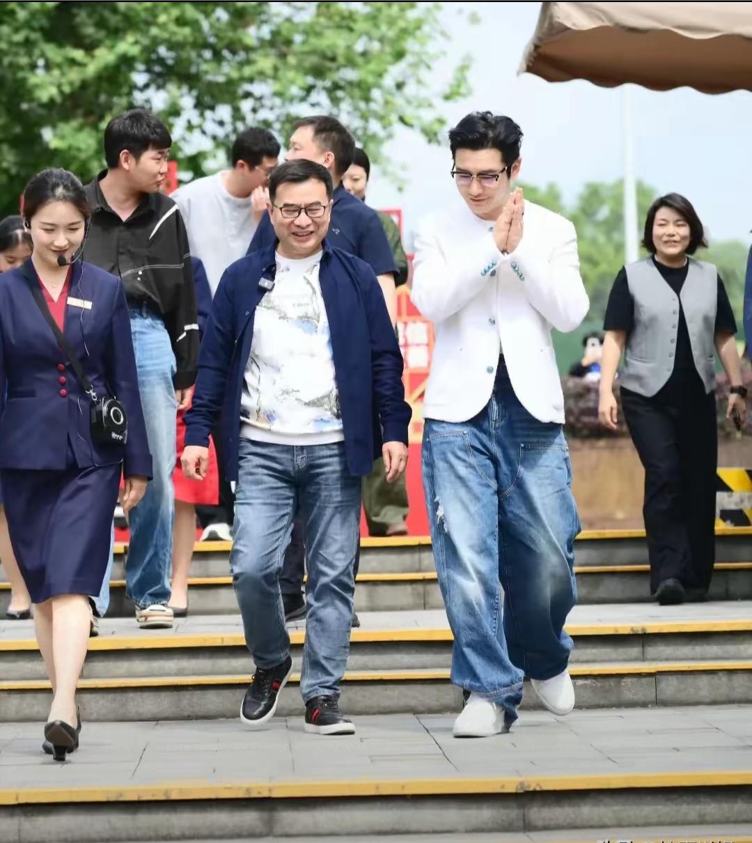 黄晓明现身四川川泸州“酒城”他梳着大背头发型，穿着一件白色外套，下身搭配宽松蓝色