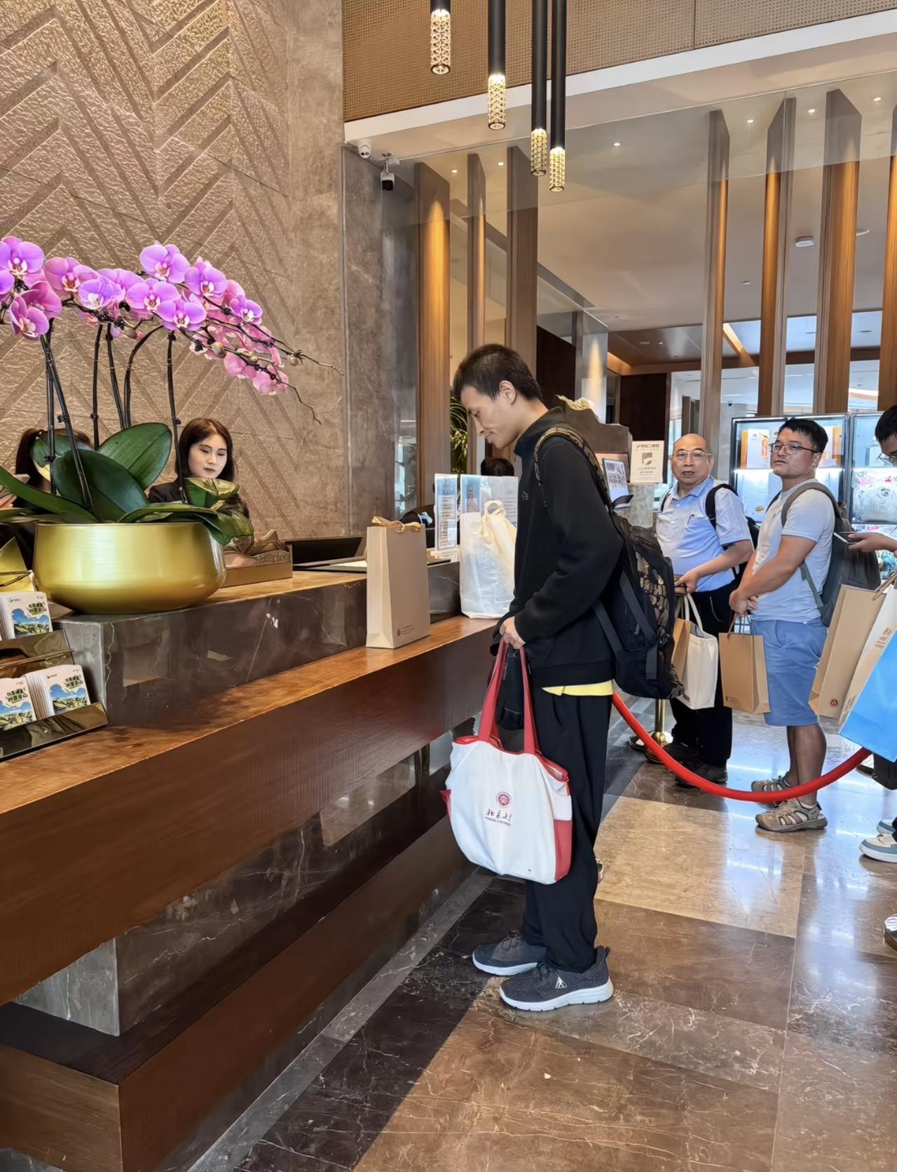 35岁韦东奕“韦神”在崇礼酒店大堂办理入住，背着大包参加数学活动，没有行李箱，拿