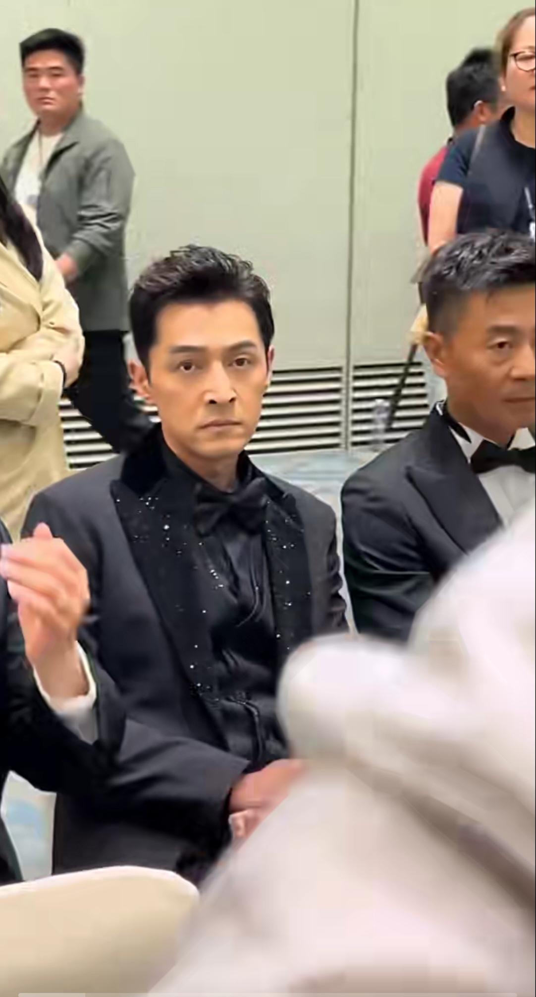 第31届上海电视节白玉兰提名晚宴候场区。胡歌身着黑翻领礼服西装，生图镜头下状