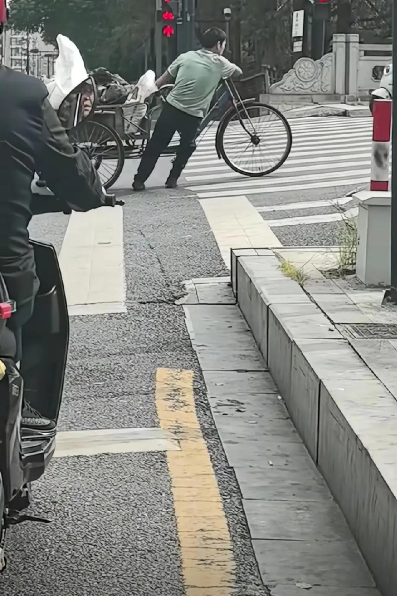 浙江杭州，一个脑瘫小伙在路口推三轮车上坡，车太重，怎么也推不上去，一辆电动车却因