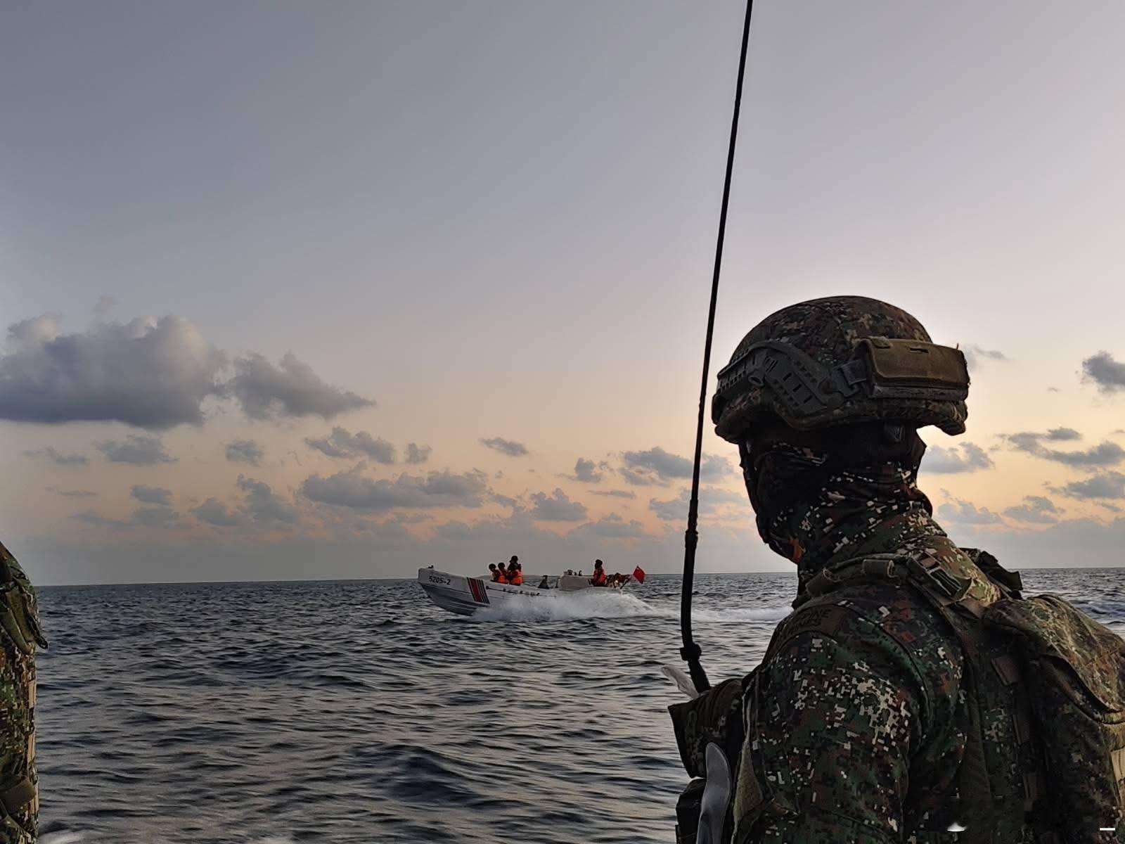 中国海警5205舰的舰载工作艇在中业岛岸边驶过，近景是岛上的菲律宾海军陆战队士兵