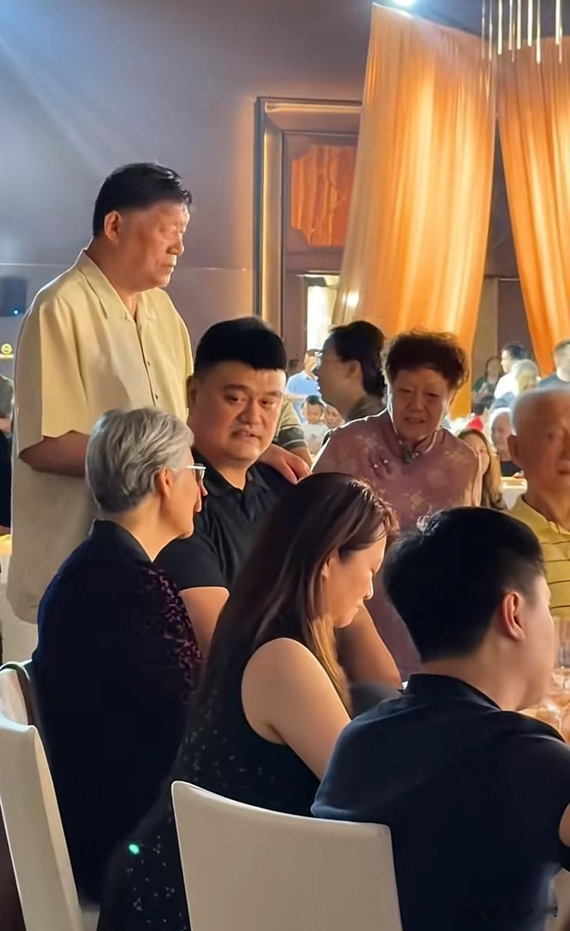 姚明回老家喝喜酒，亲戚双手搭在他肩膀上聊天，关系很亲近，姚明也很低调地坐着吃菜喝