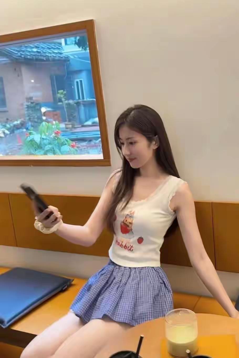 夏日的甜妹日常，卡通背心搭配蓝格短裙，元气又可爱～长发披肩，在咖啡馆里随手一拍