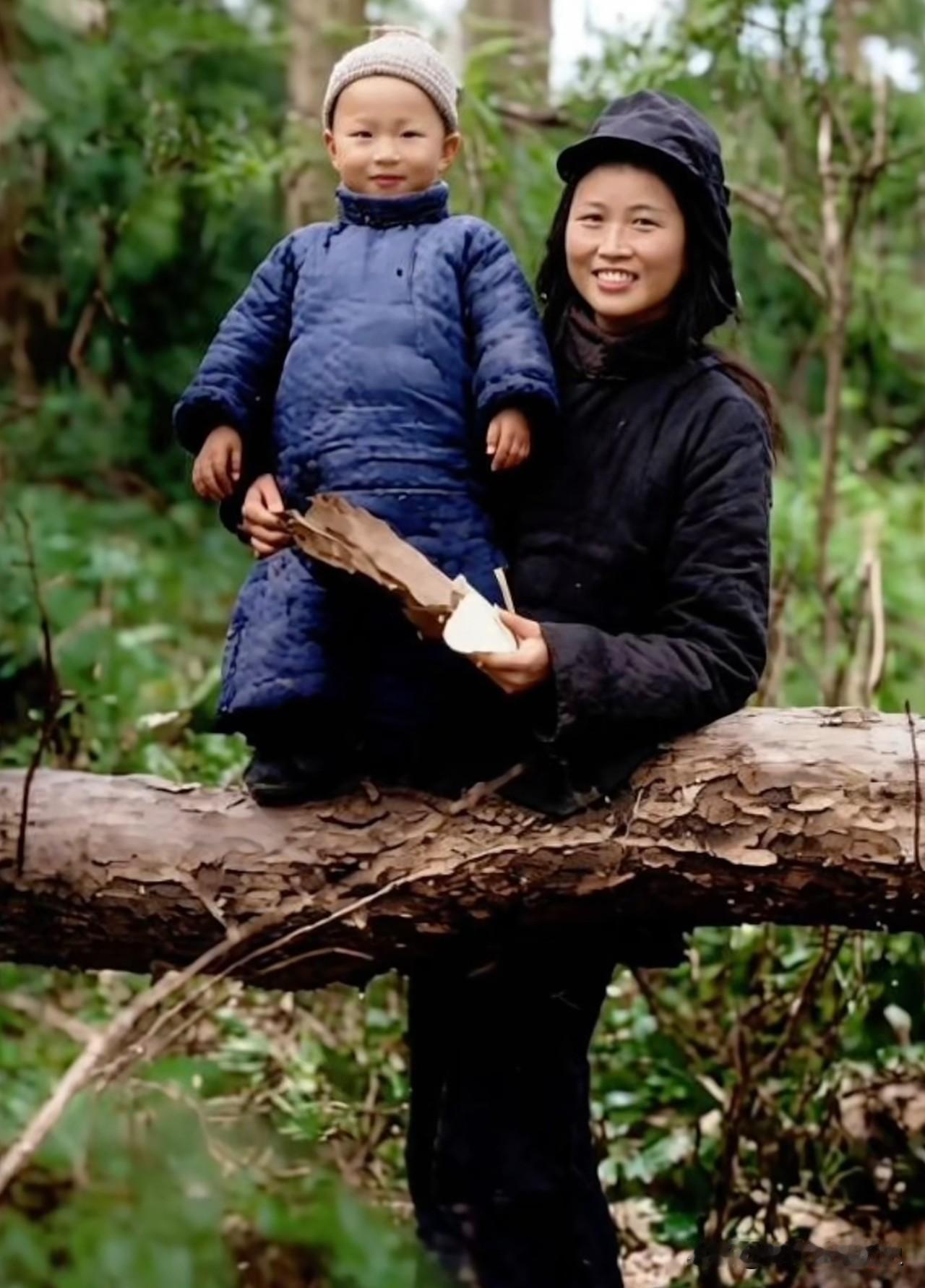 林间原木之上，楚青怀抱幼子粟戎生，一身深色棉衣，笑容温润明朗。战火年代，楚青追