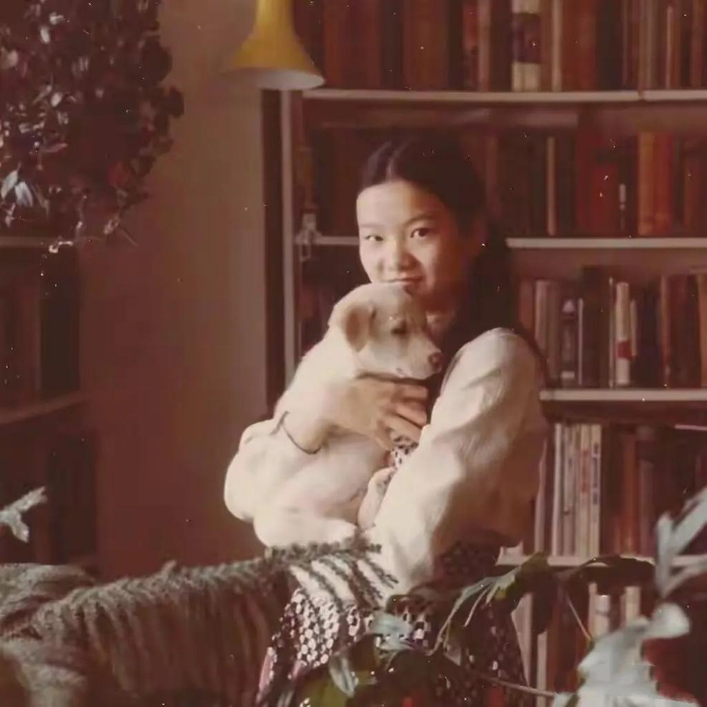 80年代，少女时期洪晃的一张留影，镜头中她在摆满了书籍和绿植的房间内，扎着双马尾