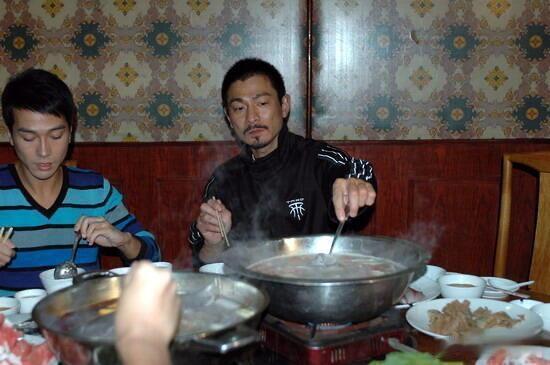 2005年，刘德华在北京拍摄电影《墨攻》时，与剧组人员一起吃涮羊肉的画面。桌