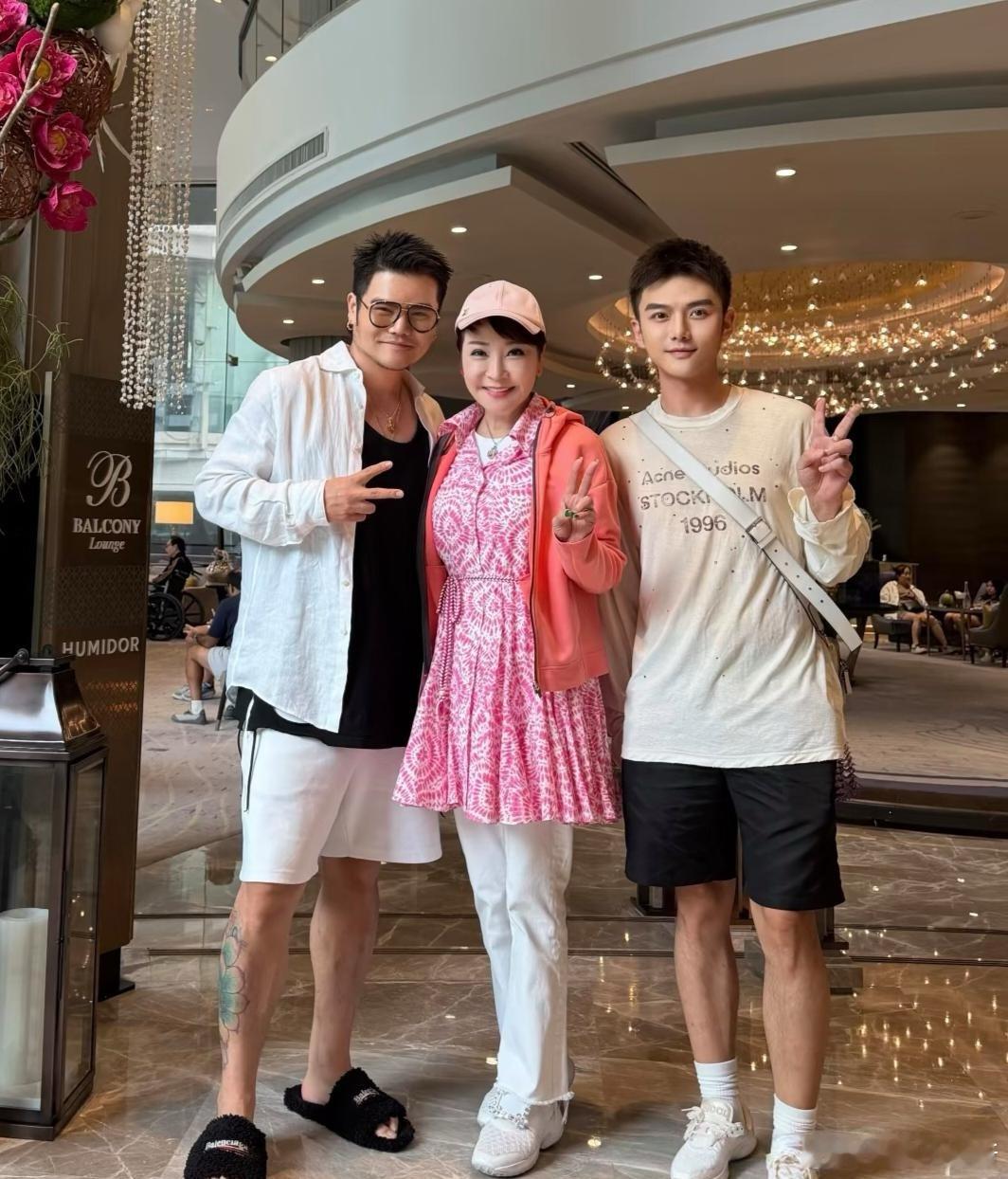 谢霆锋妈妈狄波拉和两个年轻帅哥到泰国拜四面佛，她穿着粉色裙子，外表好年轻，完全不