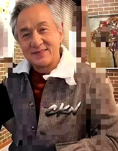 71岁成龙羡慕别人抱孙子看着朋友怀里的小娃娃，他眼睛亮了又暗，转头摸出手机翻