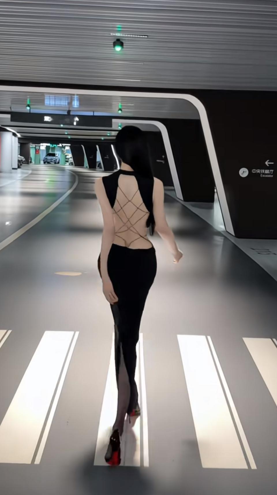 在未来感的地下通道里，她以一袭露背绑带黑裙，将性感与酷飒揉成独一份的风格，每一步