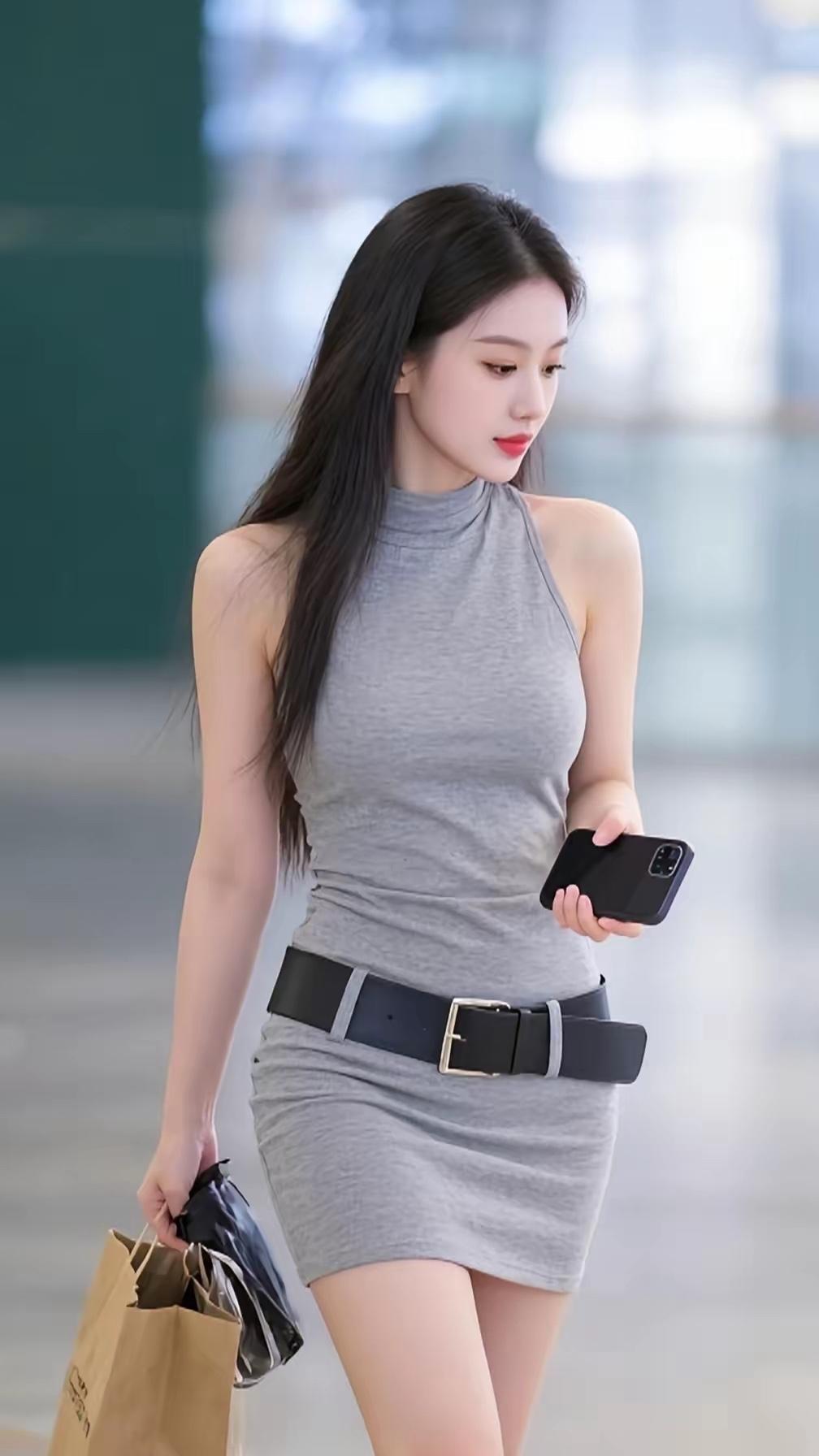 都市时尚少女，灰色连衣裙搭配黑色腰带，手拿手机和购物袋，自信走在街头。