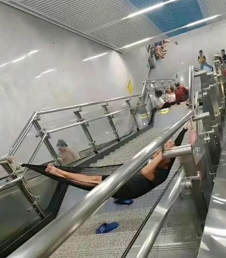 把吊床绑在地铁站楼梯栏杆上睡觉？这么蹭空调也太没分寸了！ 七月份的重庆，热浪