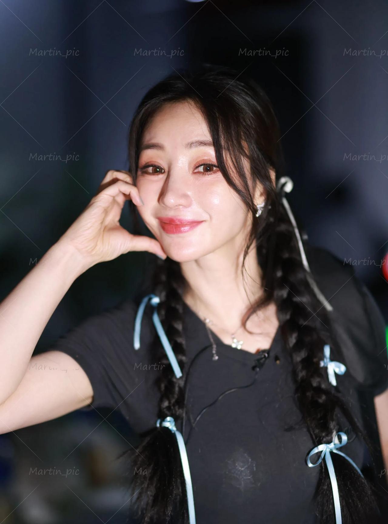 柳岩双麻花辫配黑上衣，笑时甜、皮肤亮，抱水杯互动超自然，身材凹凸藏不住，性感直接