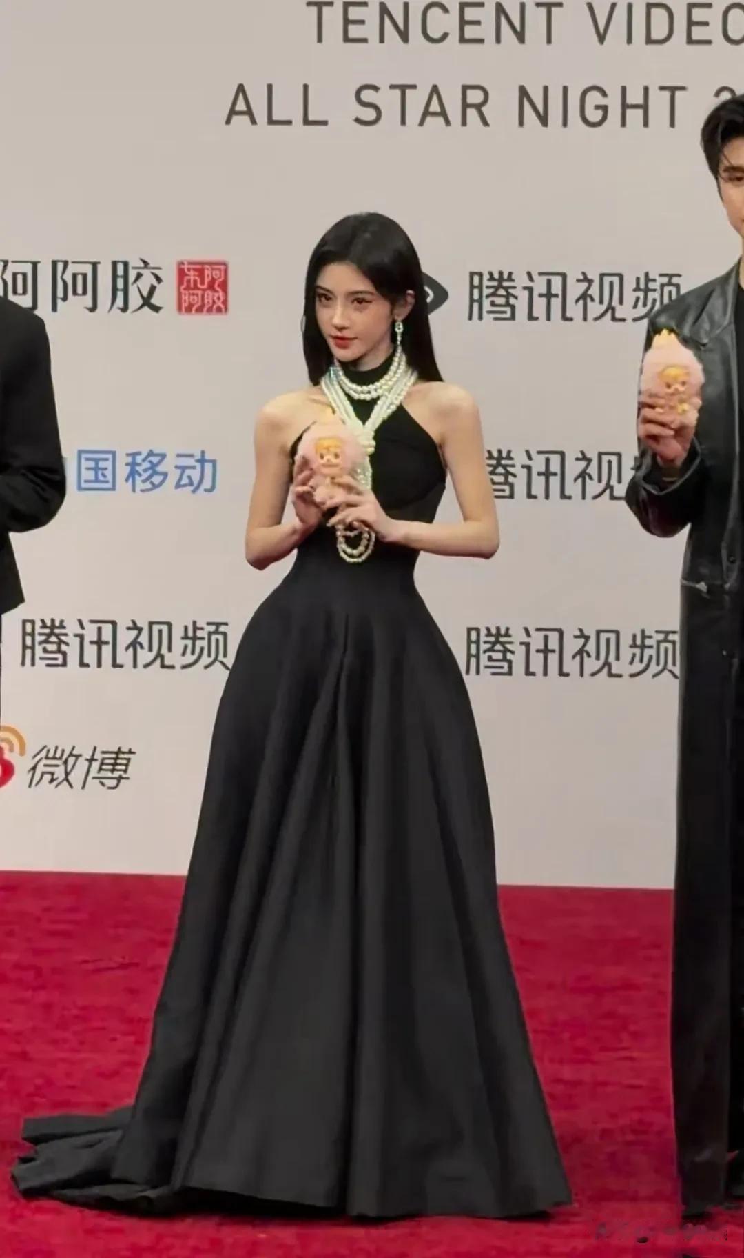 鞠婧祎参加活动“腾讯视频星光大赏”，穿着一条黑色挂脖露肩唱裙，脖子上挂了一大串珍