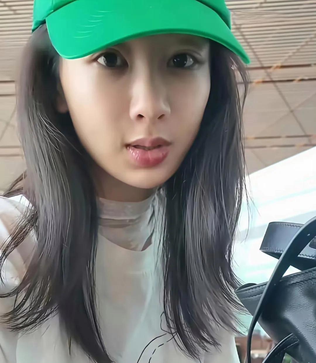 杨紫机场纯素颜出镜✨一顶绿色棒球帽，简单白T恤，没有浓妆修饰。皮肤状态透亮，
