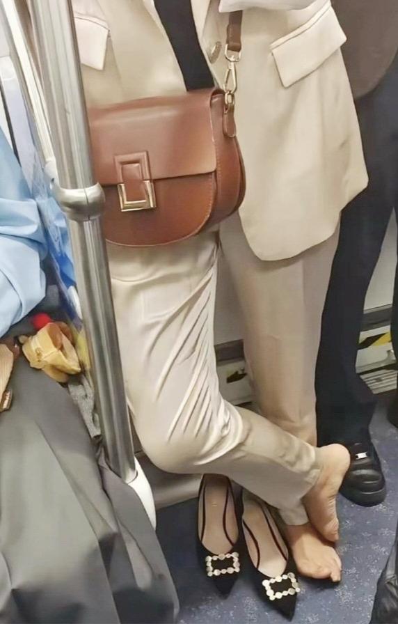 早高峰2号线，穿一身名牌西装的姑娘，突然把高跟鞋脱了，光脚直接踩在上面。旁边大爷