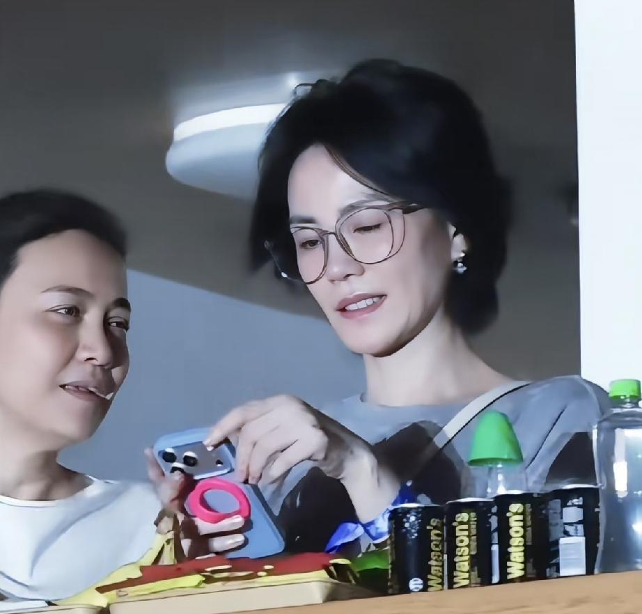 戴着眼镜的王菲和她的妈妈好像。王菲遗传了妈妈的歌唱天赋和颜值，妈妈因病去世的早