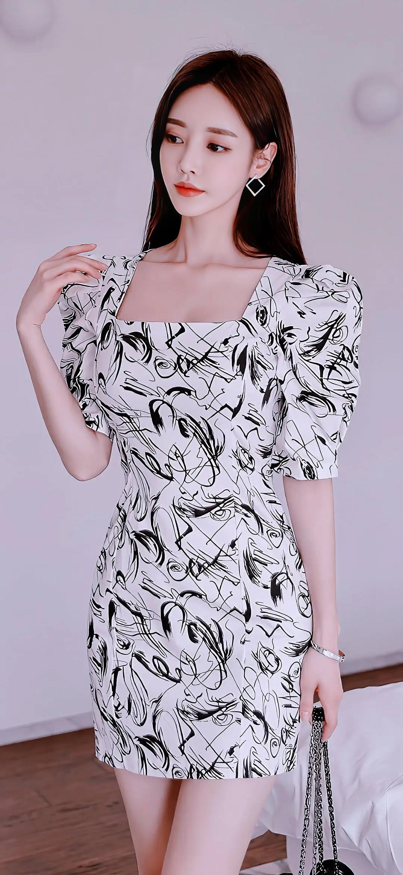 这位美女穿着时尚连衣裙，手拿小包。