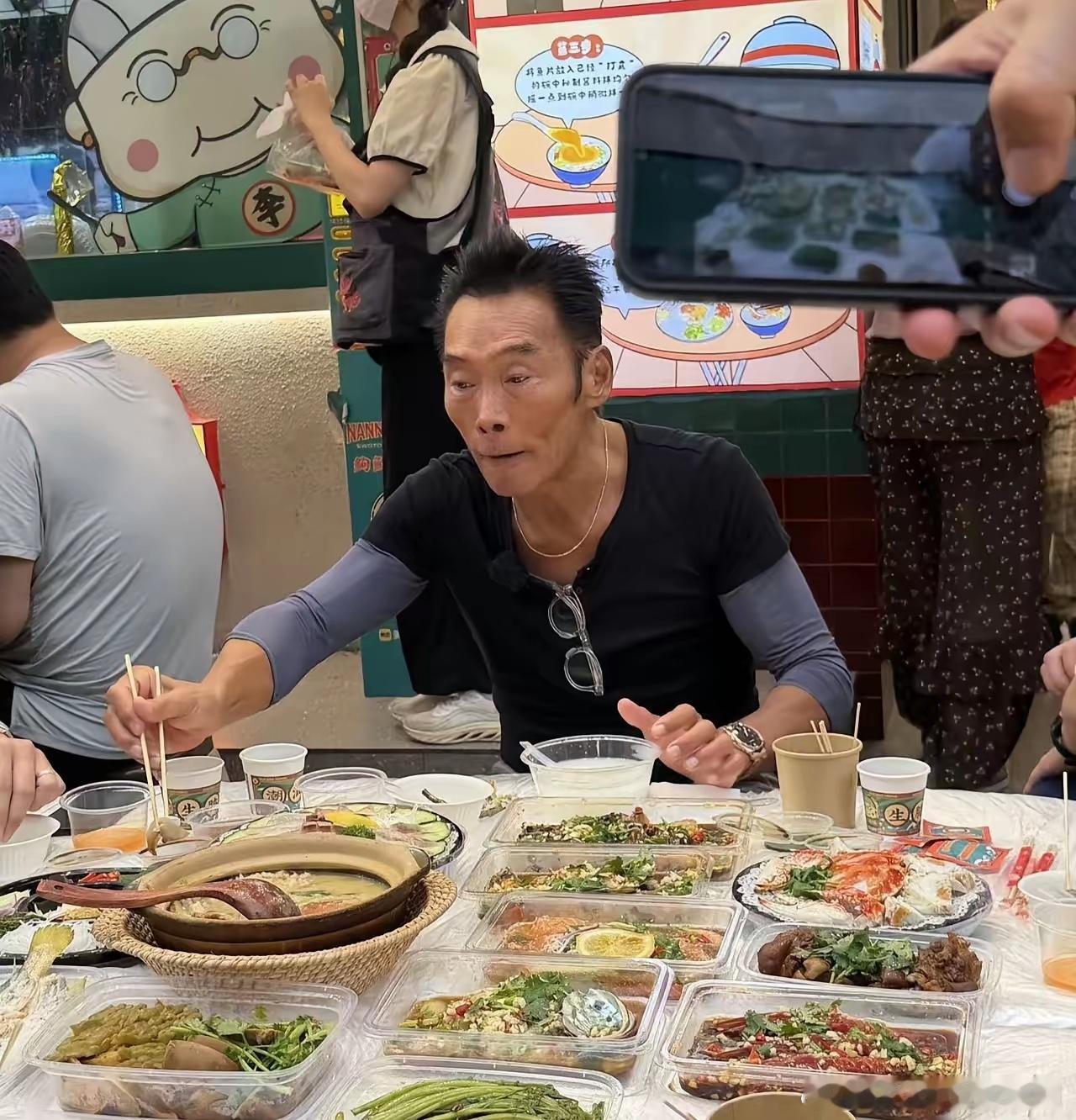 62岁港星郑浩南现身广东汕头一家餐馆吃生腌菜，他坐在街边排队，点了一大桌海鲜，在