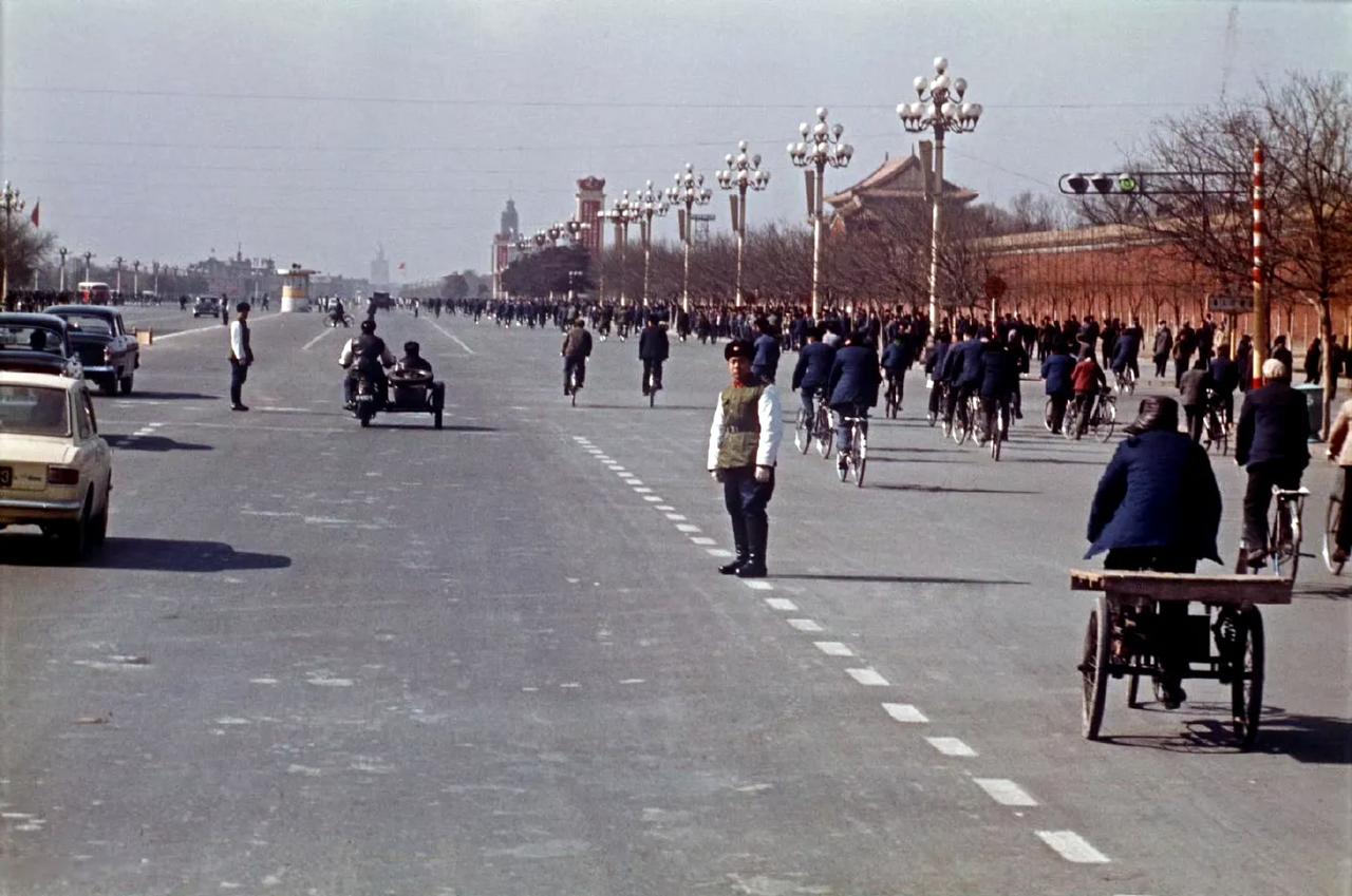 这是一张拍摄于1972年2月21日的老照片，宽阔的长安街上车流、人流交织，自行车