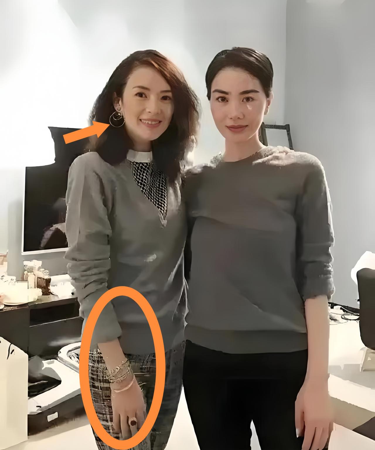 王菲和章子怡同穿灰色系衣服，章子怡配饰精致亮眼，手链、戒指、大耳环一应俱全，服装