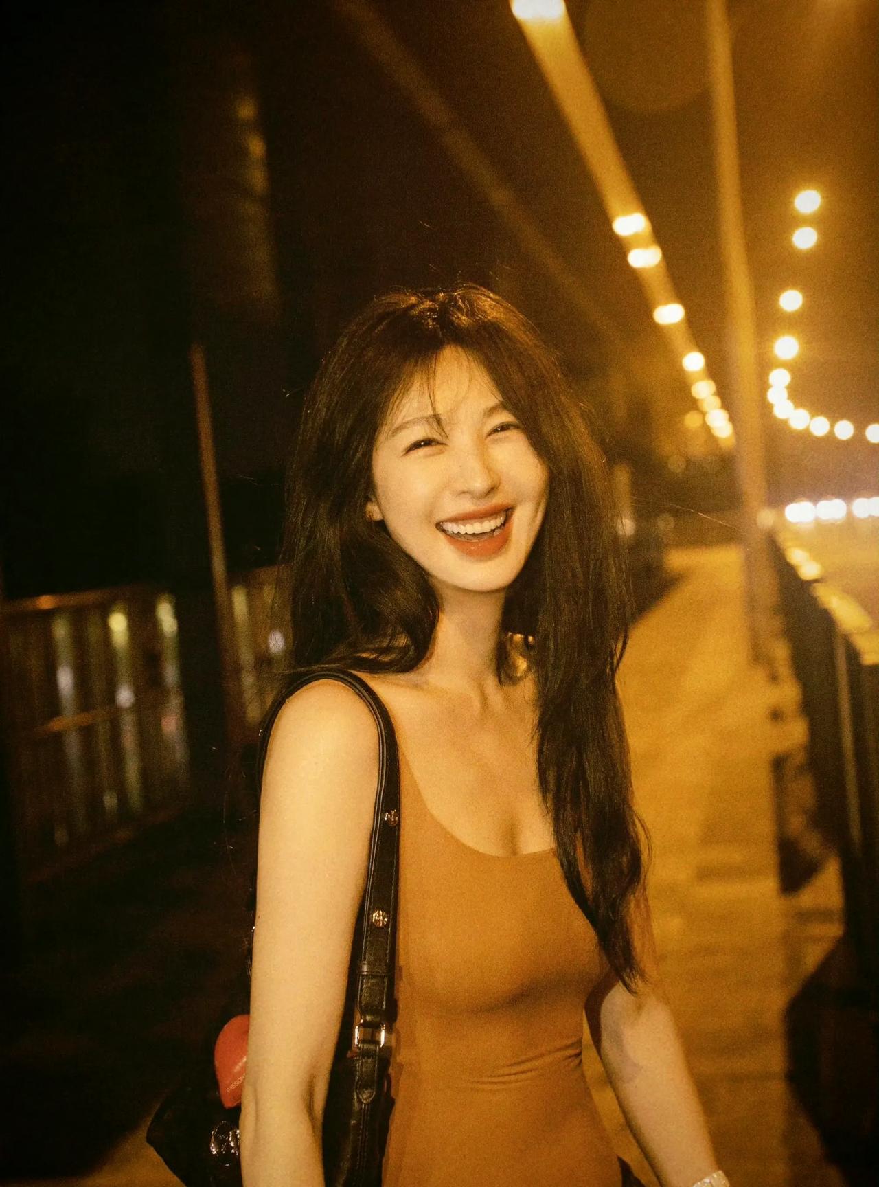 李菲儿在夜色霓虹中，将松弛美学演绎得淋漓尽致。驼色吊带贴身勾勒天鹅颈与腰肢曲线，