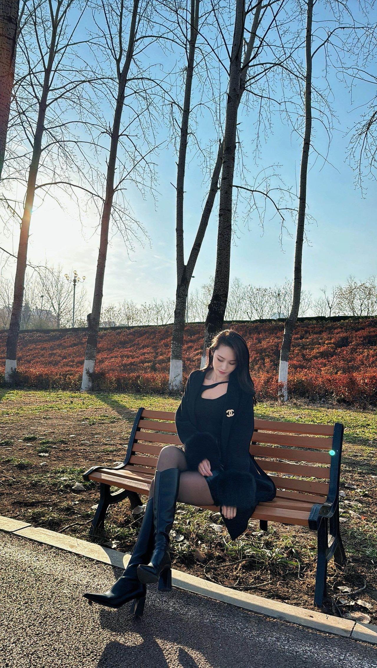 冬日公园里的时尚穿搭，黑色连衣裙与高筒靴的完美搭配，尽显优雅与自信。