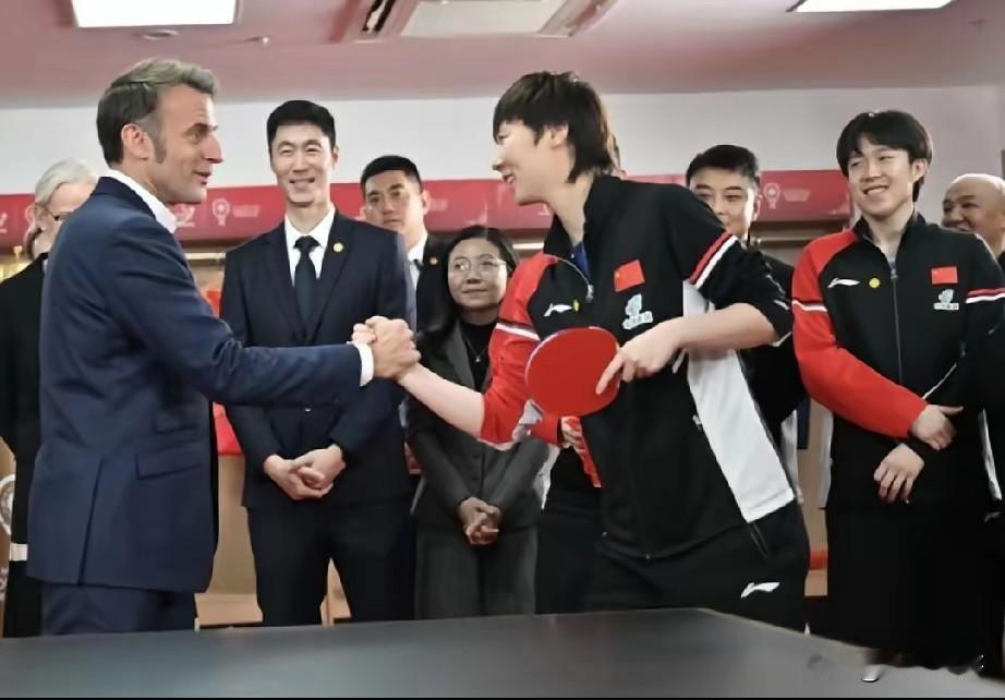 王曼昱给所有运动员上了一课王曼昱站在马克龙旁边握手时，左手握球拍，右手从容舒