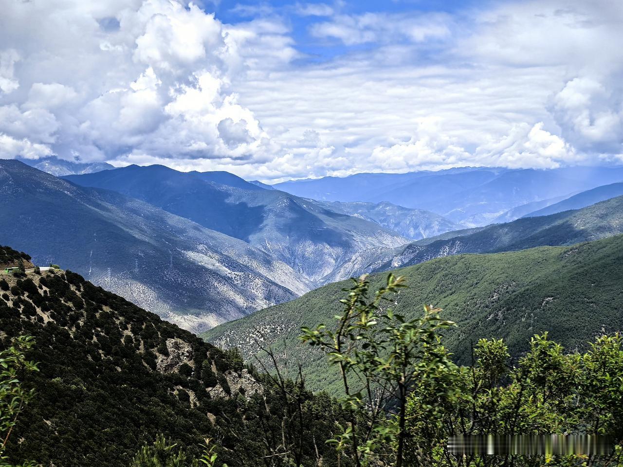 踏上去往稻城亚丁的路途，沿途层层叠叠的山峦延向远方，深浅绿意铺满峡谷。蓝天白云笼
