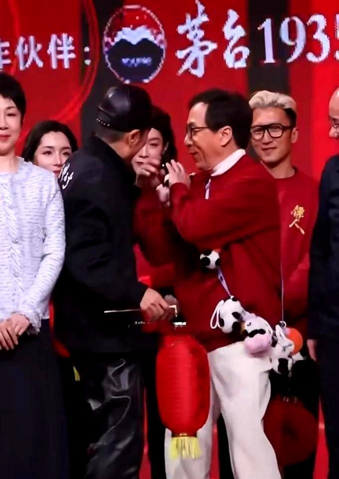 70岁成龙把张艺谋“搡”向镜头，手背青筋暴起，像押送嫌疑人。张艺谋反手扣住成龙