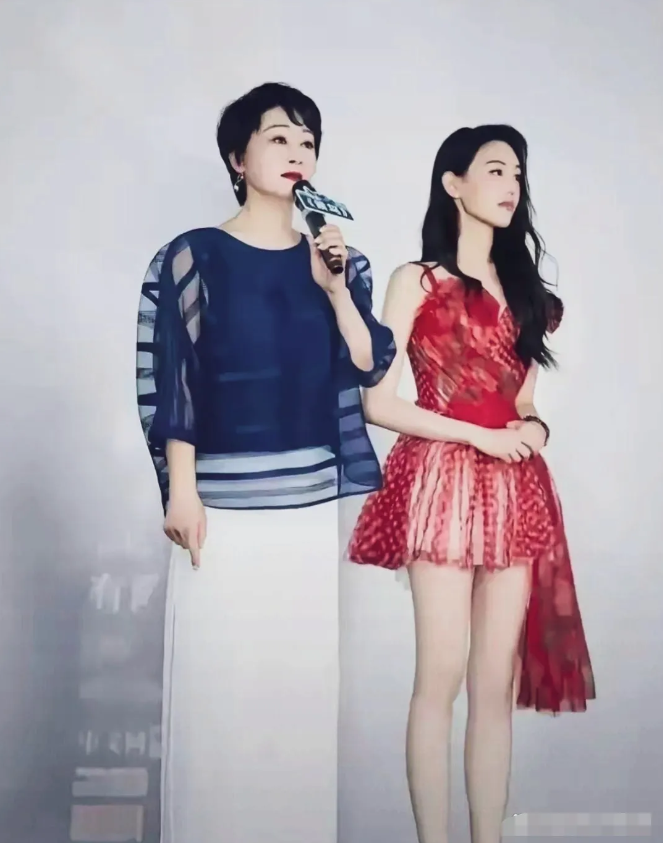 王姬与女儿同框，妈妈，蓝色上衣配白色裤子，短发造型，气质沉稳，女儿红色礼服长卷发