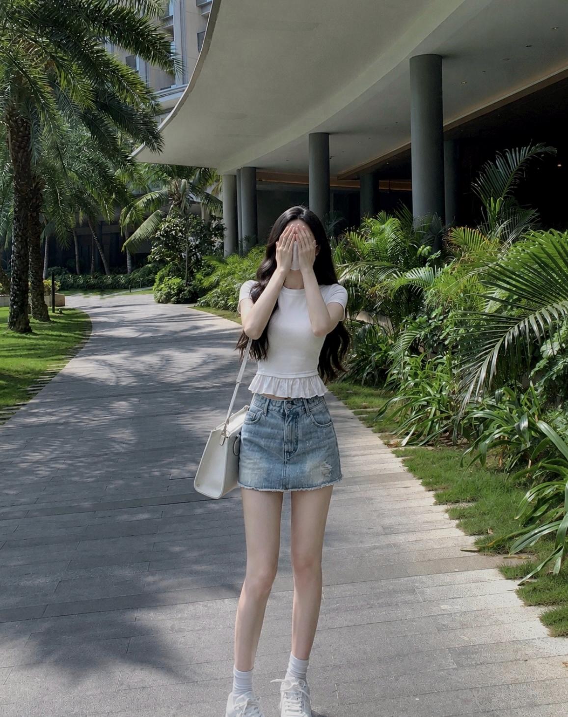 阳光明媚的午后，少女在绿意盎然的小径上，轻掩面庞，享受宁静时光。