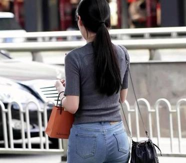 捕捉街头时尚瞬间，她休闲地迈着步子，手里提着购物袋，展现出日常的优雅。