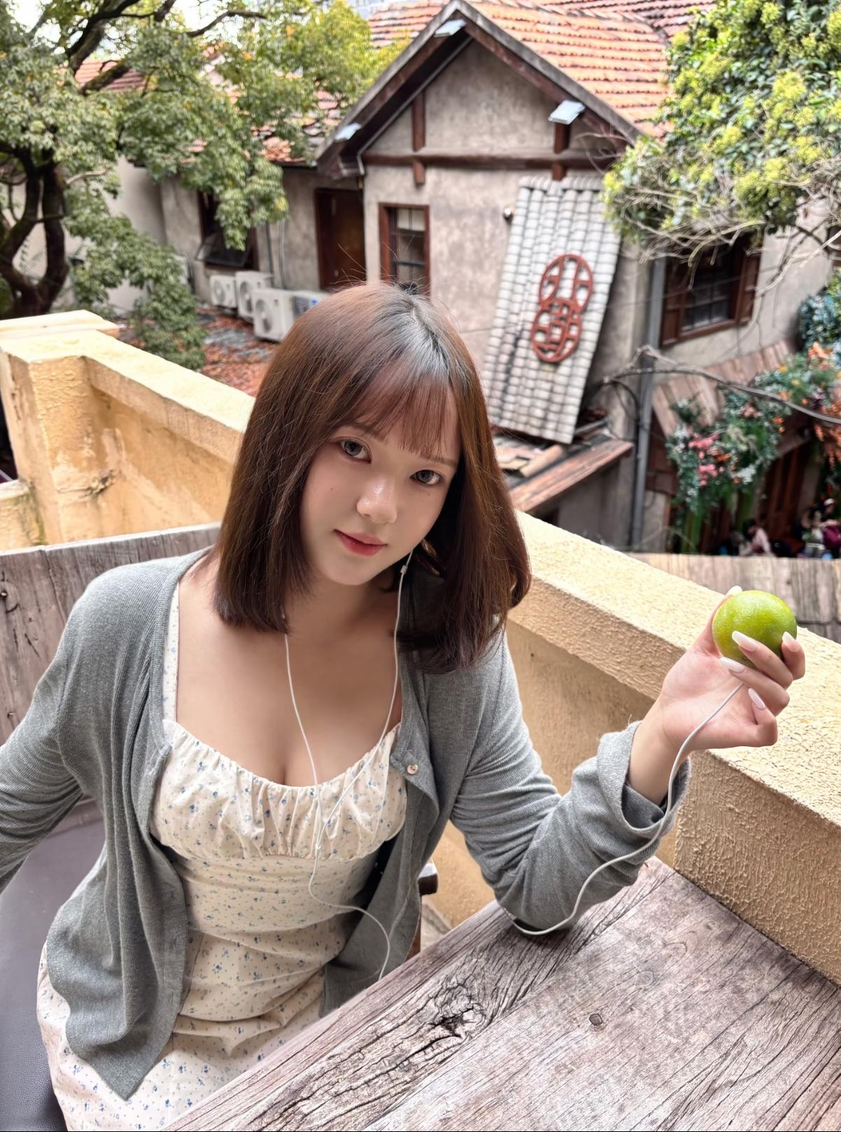 小姑娘拿了一个桔子在听歌。