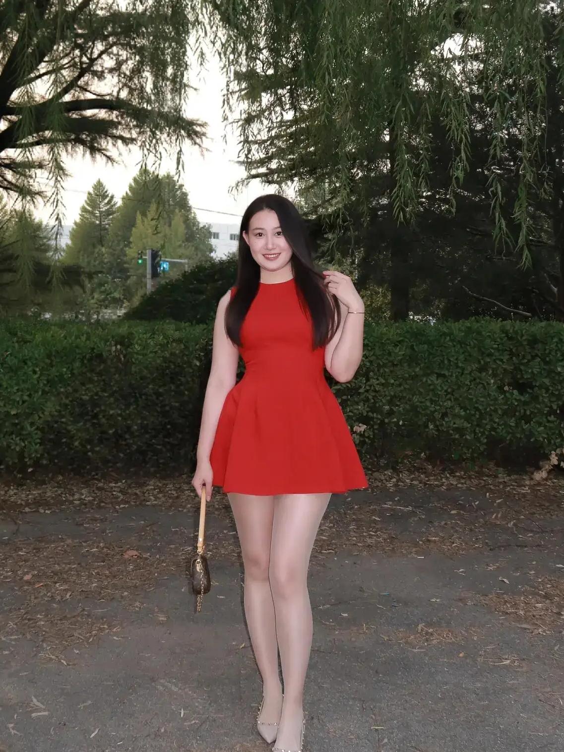 微胖女士的穿搭中，红色连衣裙搭配银灰色高跟鞋，更能凸显青春活力。手中的小挎包精致